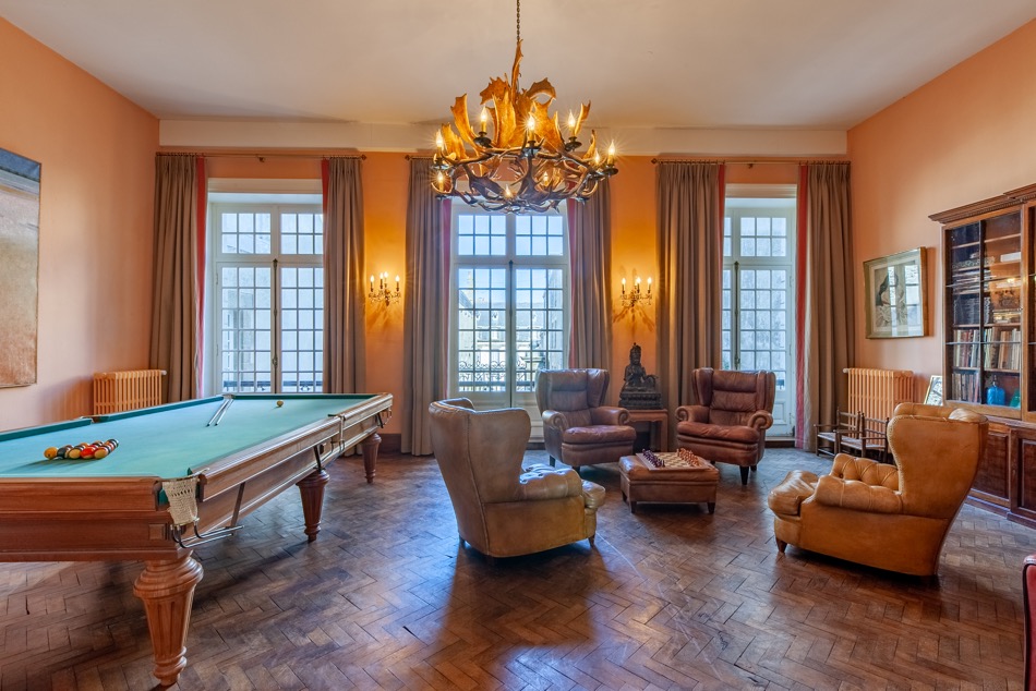 Grand salon avec billard, parquet en chevrons et lustre ancien